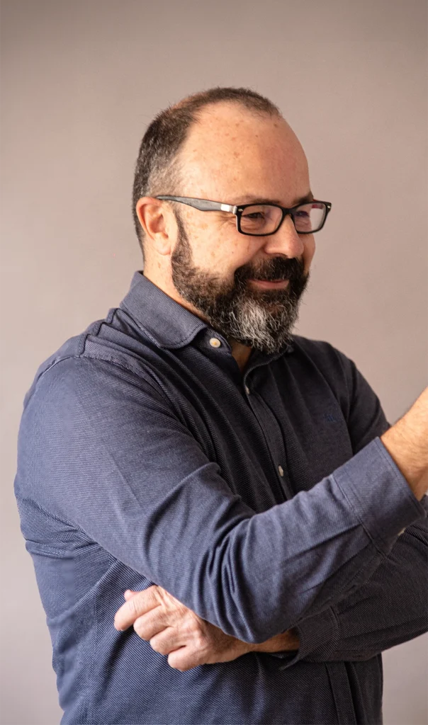 Retrato de Juan Pastor Bustamante, consultor de creatividad e innovación, en perfil, con camisa azul y fondo neutro.