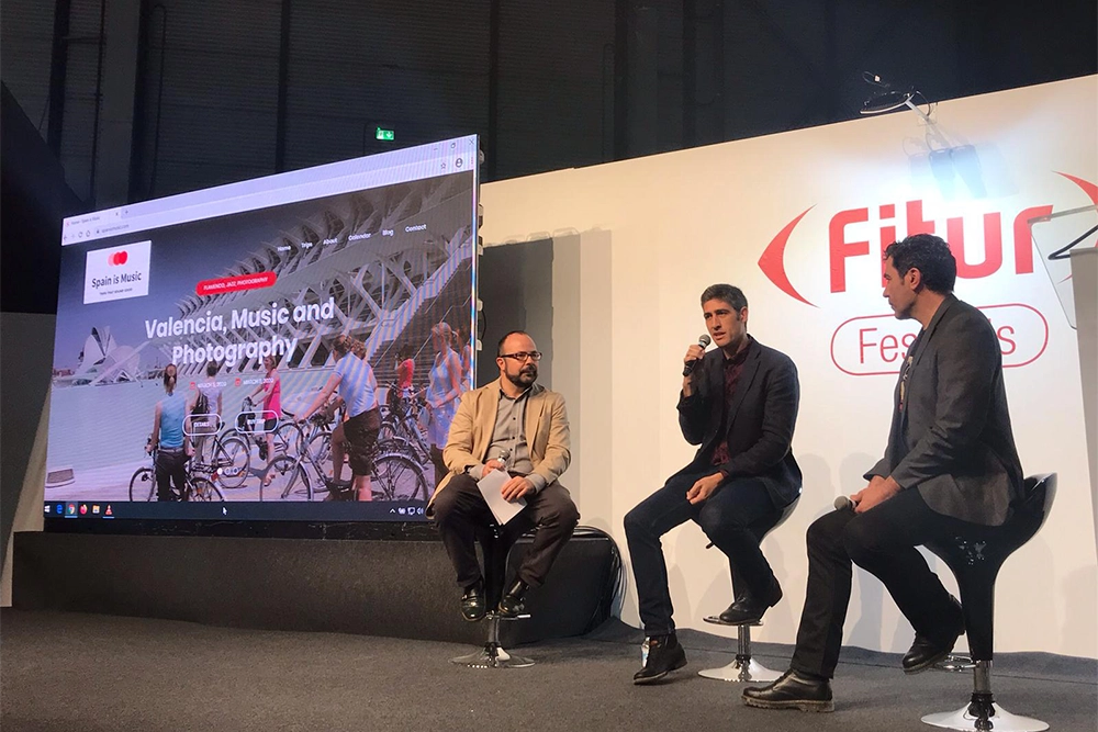 Mesa redonda en escenario con tres ponentes, entre ellos Juan Pastor Bustamante, y pantalla grande, sobre inspiración práctica.